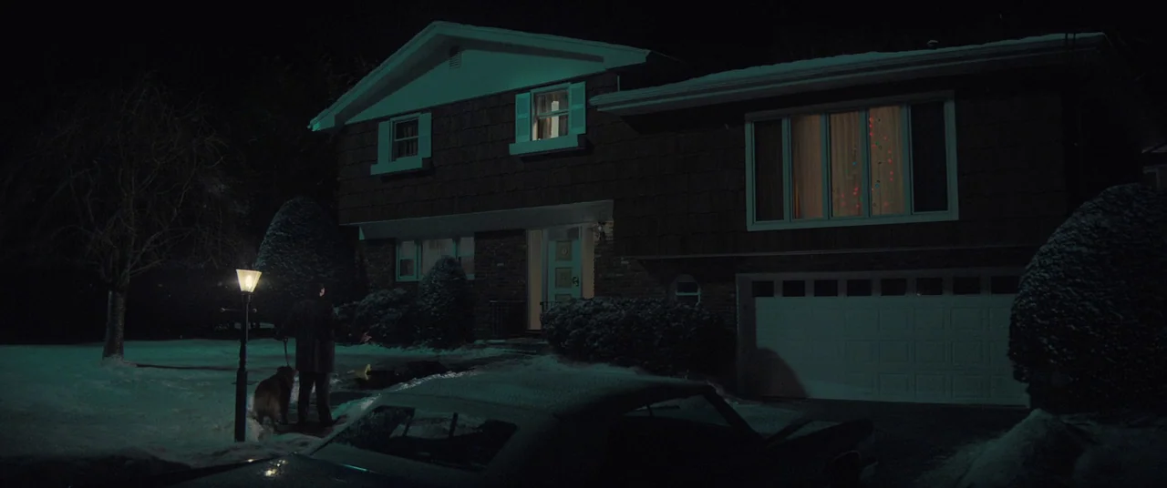 The Many Saints of Newark (2021) movie still: wide — A dark, snow-covered suburban front yard features a split-level brick house at night. A lone…