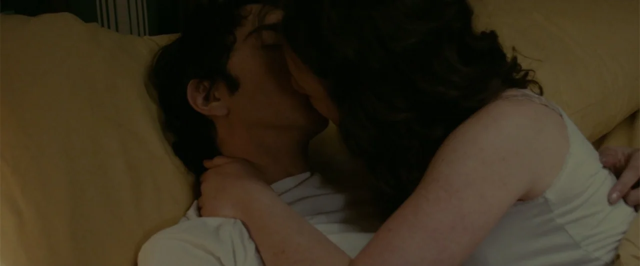 Coming Through the Rye (2016) movie still: closeup — A dark bedroom with yellow pillows and white sheets provides a backdrop. A couple lies in bed…