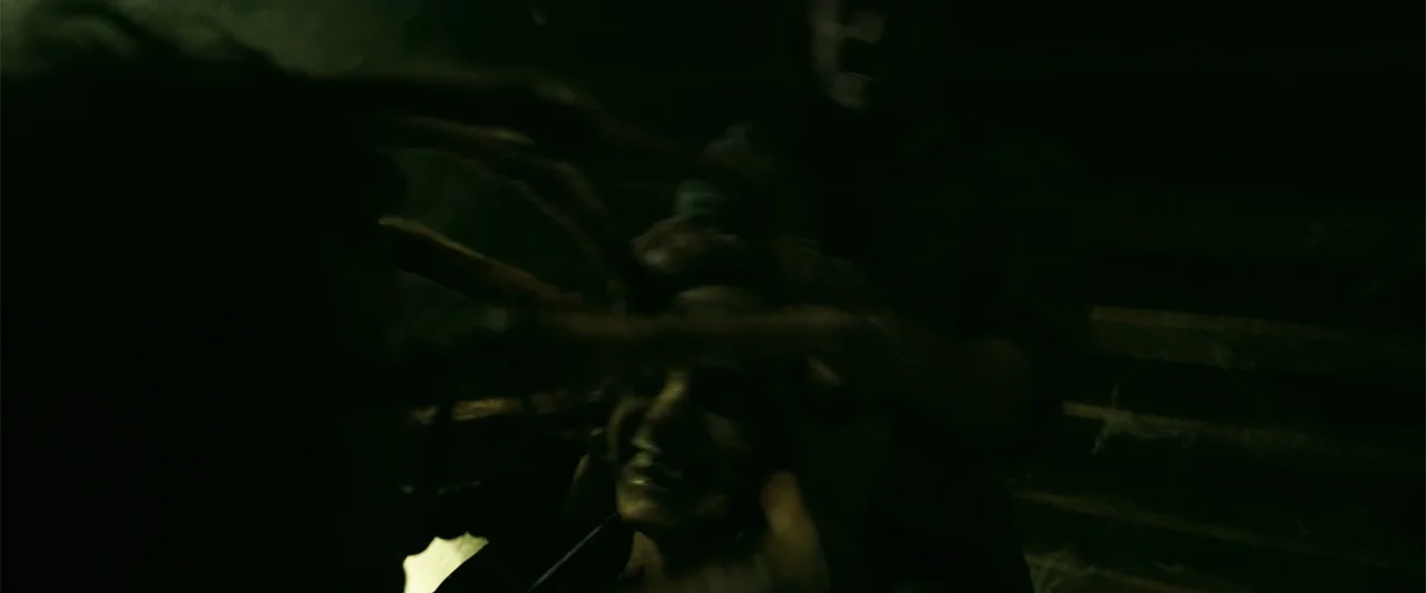 K.G.F: Chapter 2 (2022) movie still: closeup — A dark, indoor space with low lighting obscured by heavy shadows. Two people grapple with each other…
