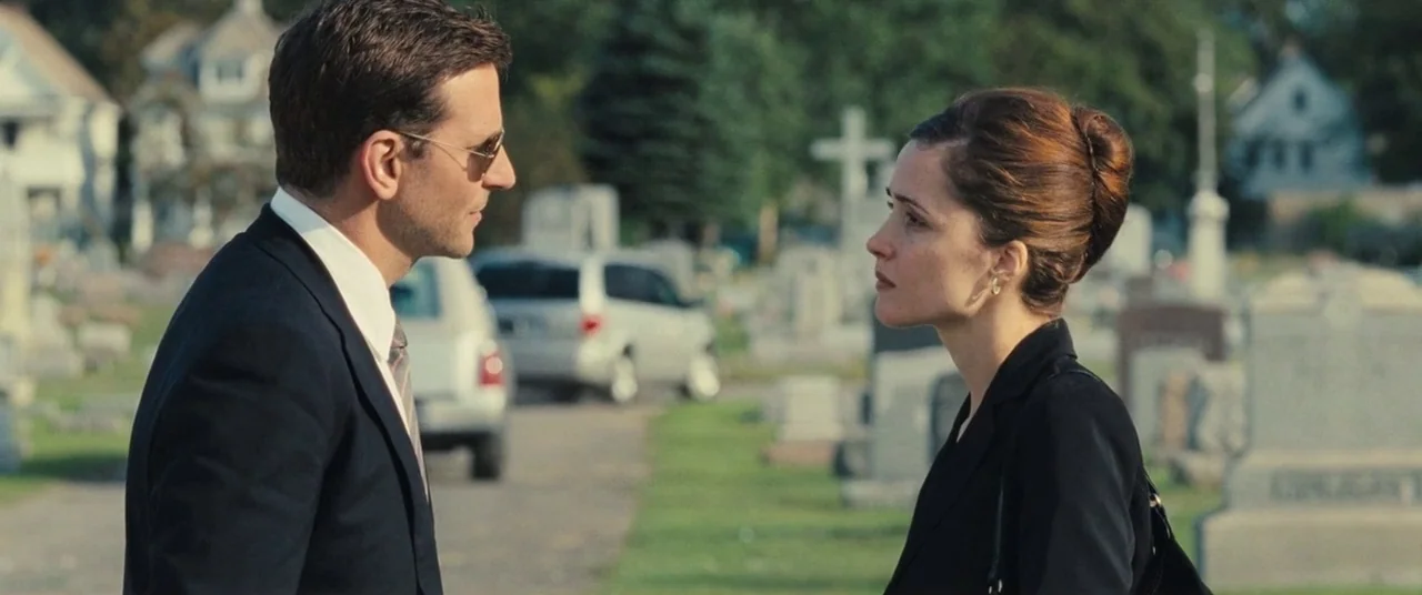 The Place Beyond The Pines (2012) movie still: medium — A man and woman stand facing each other in an open lawn cemetery. Various gravestones and…