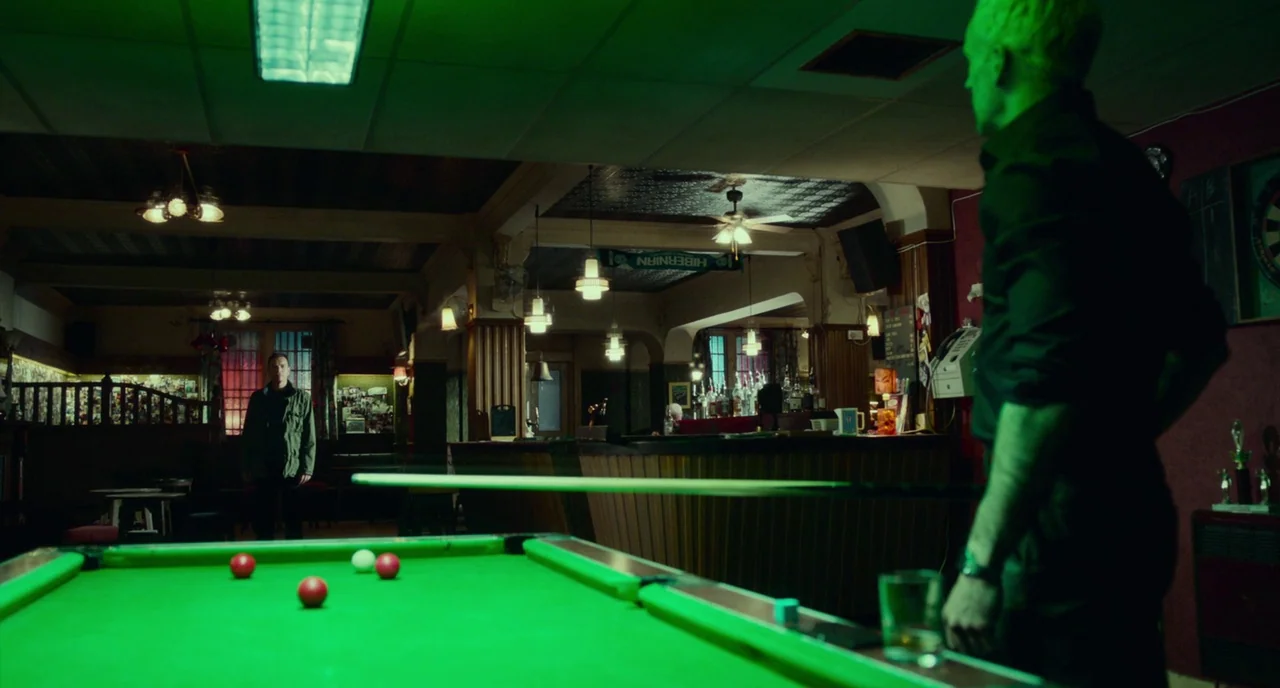 T2 Trainspotting (2017) movie still: medium — A dimly lit traditional pub features wooden furniture and a green felt pool table. Two men face each…