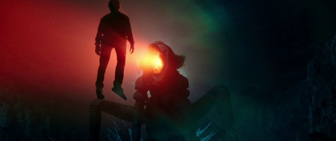 It Chapter Two (2019) movie still: wide — A dark, cavernous space is dimly lit by contrasting colored light sources. A humanoid creature with an…