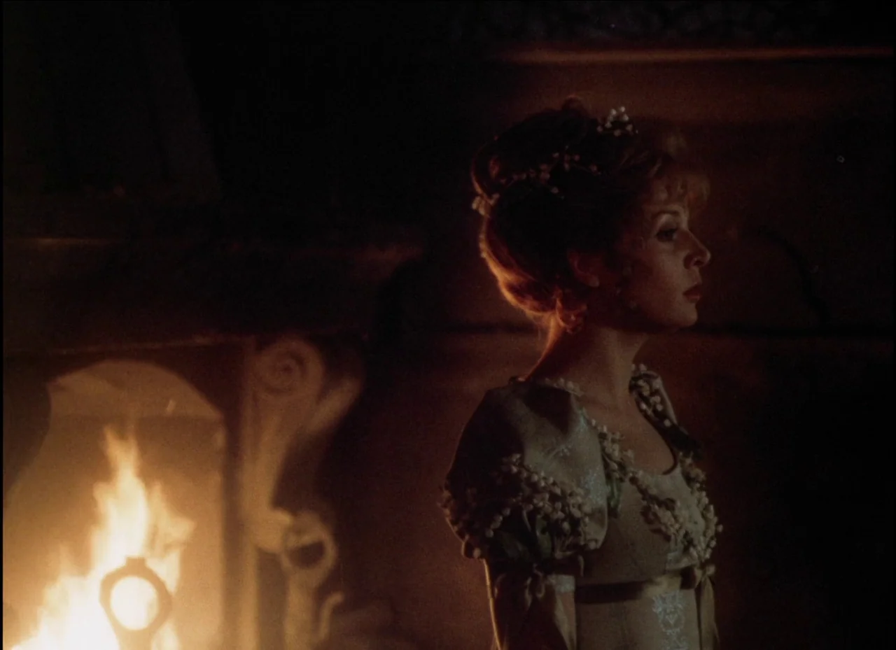 Beauty and the Beast (1979) movie still: medium — A woman stands in a dimly lit room with stone fireplace architectural features. She looks toward…