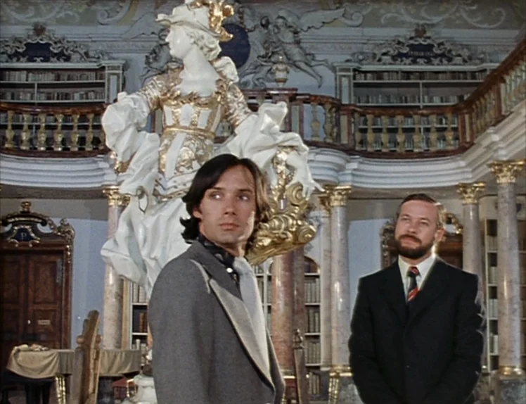 Martha (1974) movie still: medium — A baroque interior features elaborate gold-gilded carvings and tiered bookshelves lining the upper walls. Two…