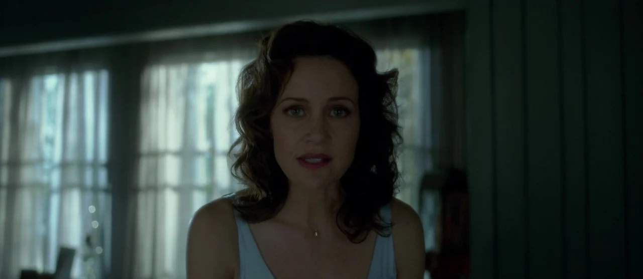 Gerald’s Game (2017) movie still: medium — A woman stands in a living room with draped windows visible in the background. She faces the camera…
