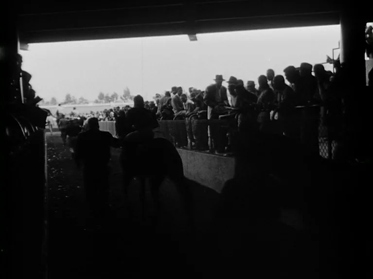 The Killing (1956) movie still: wide — A dark concrete tunnel leads out to a bright, sunlit horse racing track. A lone rider on horseback walks away…