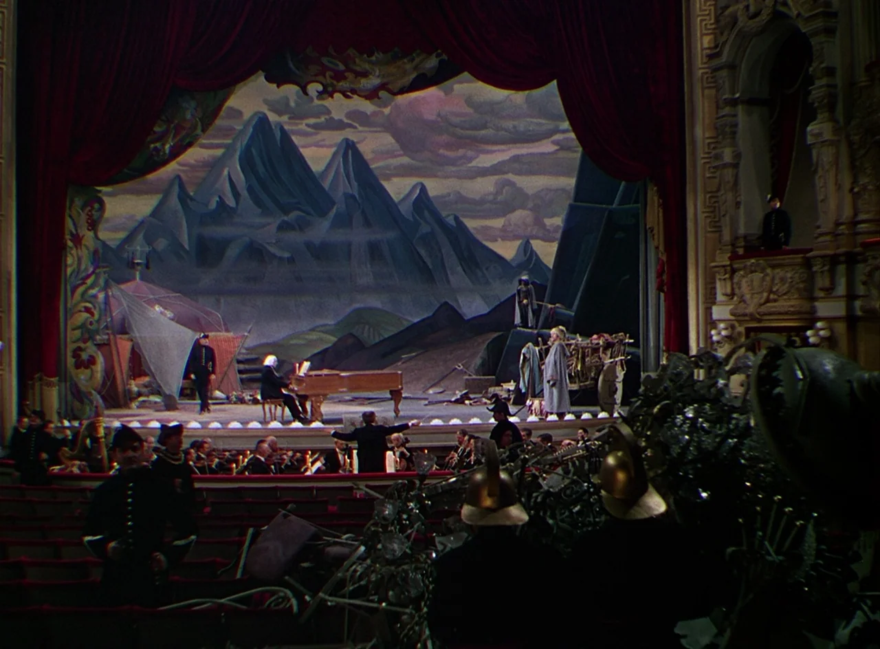 Phantom of the Opera (1943) movie still: wide — An opulent opera house features a large painted stage backdrop depicting craggy mountain peaks.…