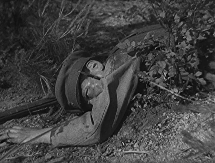 No Regrets for Our Youth (1946) movie still: medium — A soldier lies face down on a patch of uneven, dry ground. The figure is positioned among…