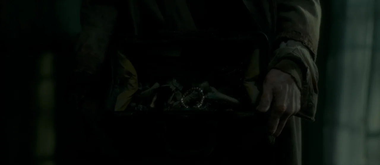 Gerald’s Game (2017) movie still: closeup — A dark space holds a person in a brown worn coat holding an open bag. The bag contains animal or human…