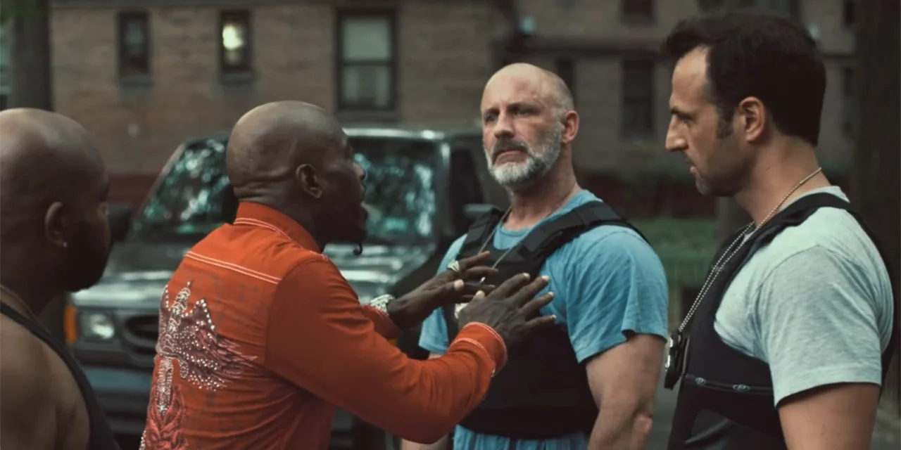 Equal Standard (2021) movie still: medium — A group of men stand on a residential city street near a parked SUV. One man in a red shirt speaks while…