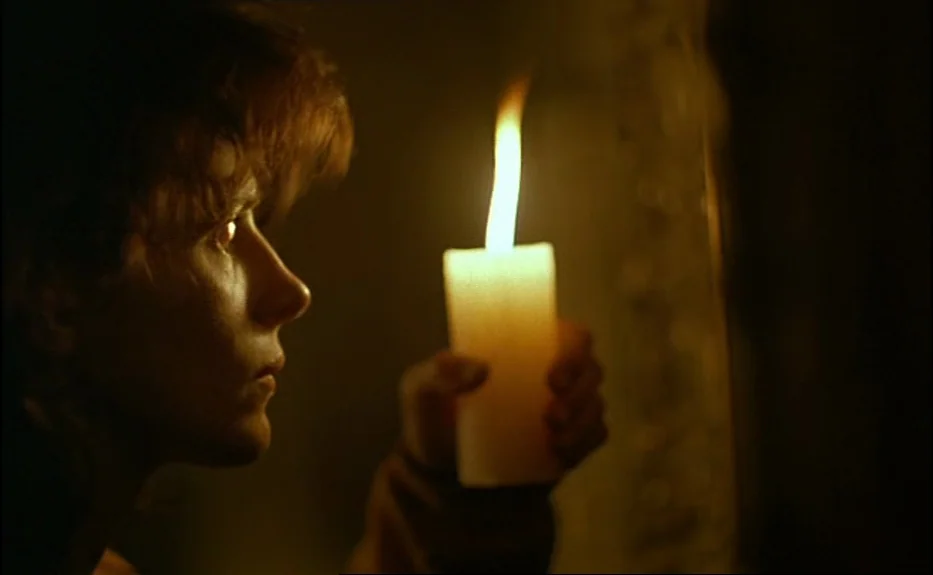 Les Amants Du Pont Neuf (The Lovers on the Bridge) (1991) movie still: closeup — A dimly lit interior space is swallowed by darkness. A young man…