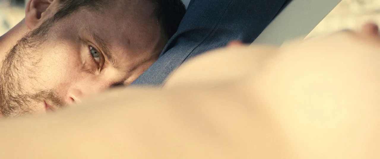 Rust And Bone (2012) movie still: closeup — A close perspective shows a man lying beside an out-of-focus body. The man looks toward the frame while…