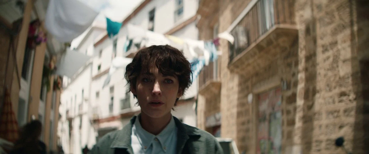 The Rhythm Section (2020) movie still: medium — A narrow European-style alleyway features stone walls and clotheslines hanging between white…