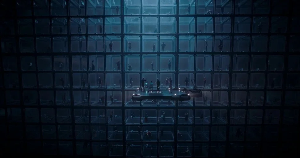 Superman (2025) movie still: wide — A vast vertical grid consists of dozens of glowing individual glass-walled cells. People occupy many of the…