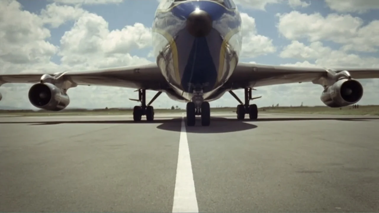 Hare Krishna! The Mantra, the Movement and the Swami Who Started It All (2017) movie still: wide — A large passenger jet sits on a paved runway…