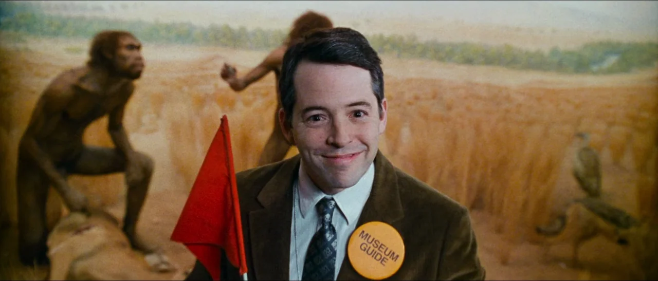 Election (1999) movie still: A museum guide stands perfectly centered in a medium close-up, his friendly expression contrasting with the prehistoric…