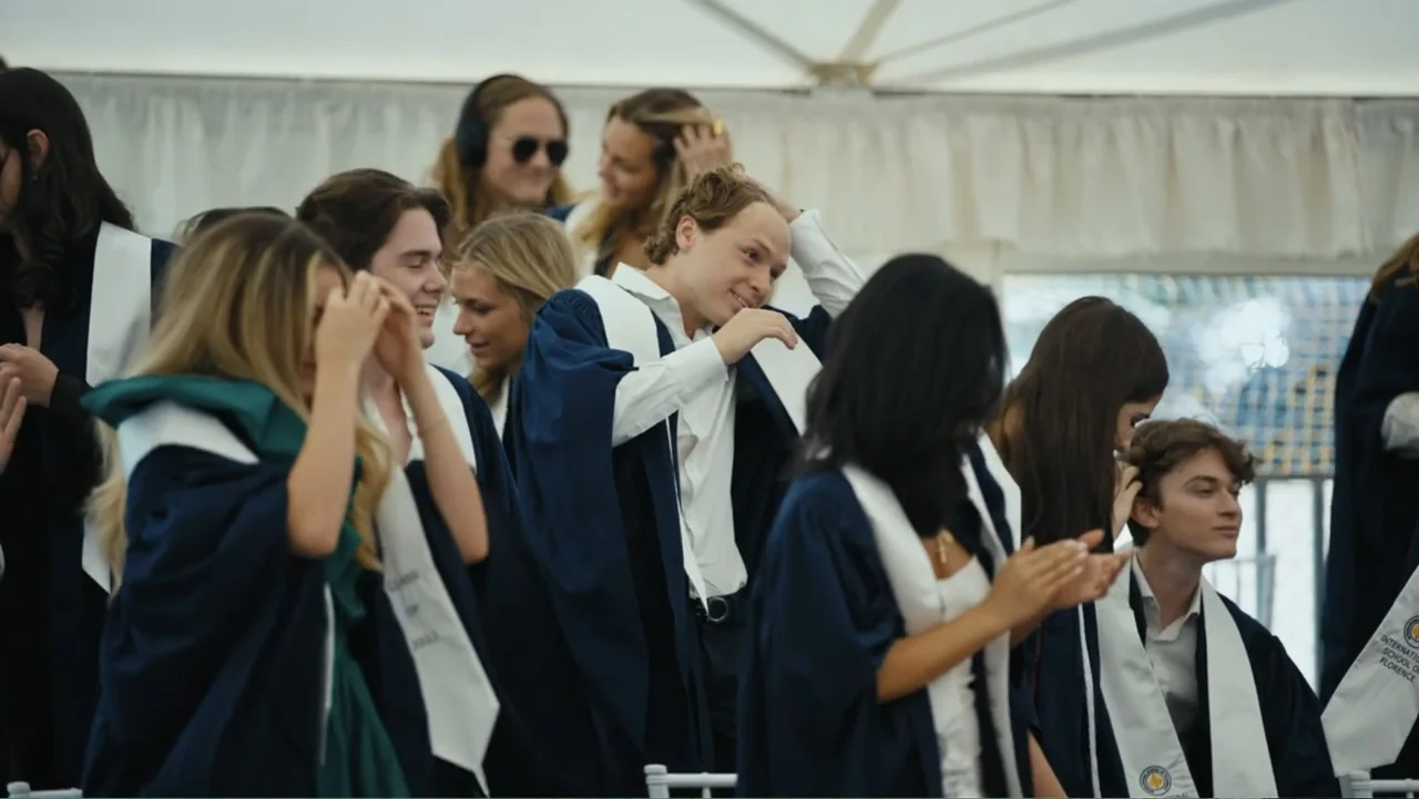 Federico Chiesa - Back on Track (2023) movie still: medium — A group of young people wear graduation gowns under a large white canopy structure.…