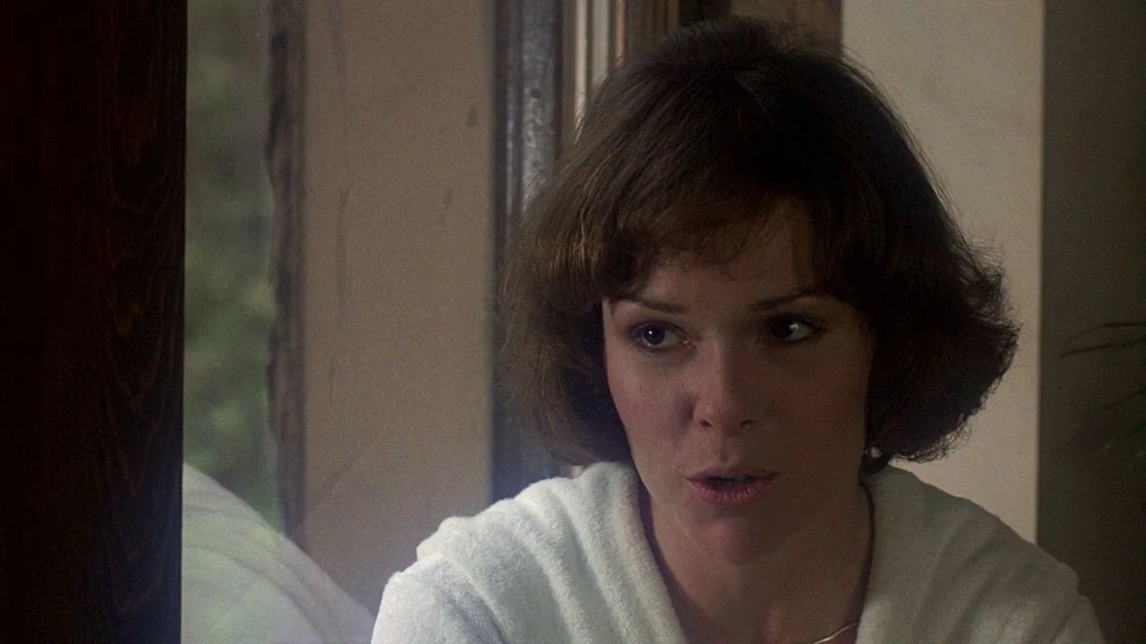 Saturday Night Fever (1977) movie still: closeup — A woman stands indoors near a wooden-framed window during the day. She is wearing a white robe…