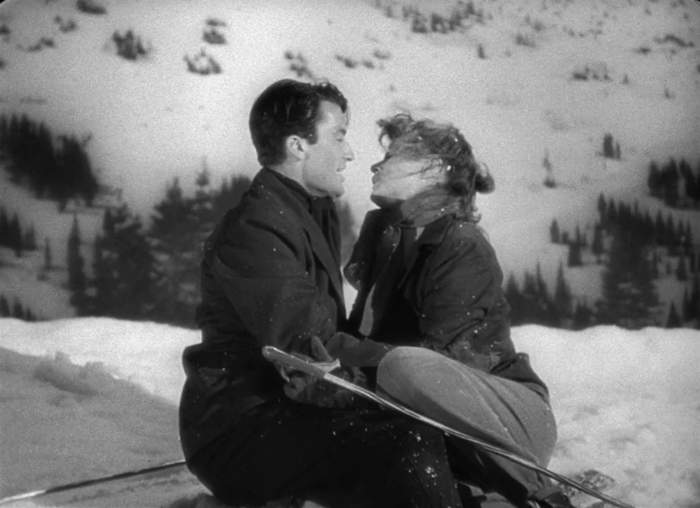 Spellbound (1945) movie still: medium — A snowy mountain slope with scattered trees on the hillside behind the subjects. A man and a woman sit…