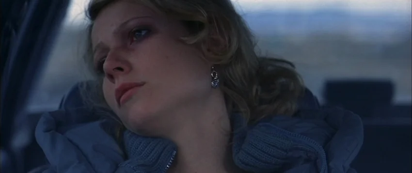 Hard Eight (1996) movie still: closeup — A view inside a moving car featuring an overcast sky through the window. A young woman with blonde hair…