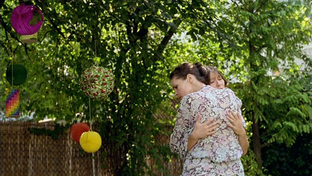 In A Year Of Thirteen Moons (1978) movie still: medium — A backyard setting features dense green foliage and colorful hanging paper lanterns. Two…