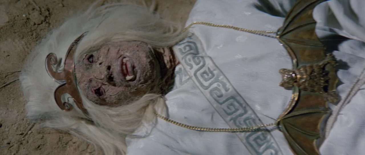 The Legend of the 7 Golden Vampires (1974) movie still: closeup — A figure with a decayed face lies on a patch of dry dirt ground. They are dressed…