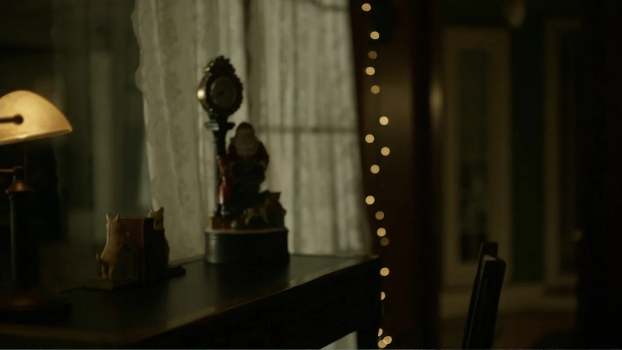A Carpenter Christmas Romance (2024) movie still: medium — A dark wooden surface holds a small decorative clock and a pair of bookends. A lace…