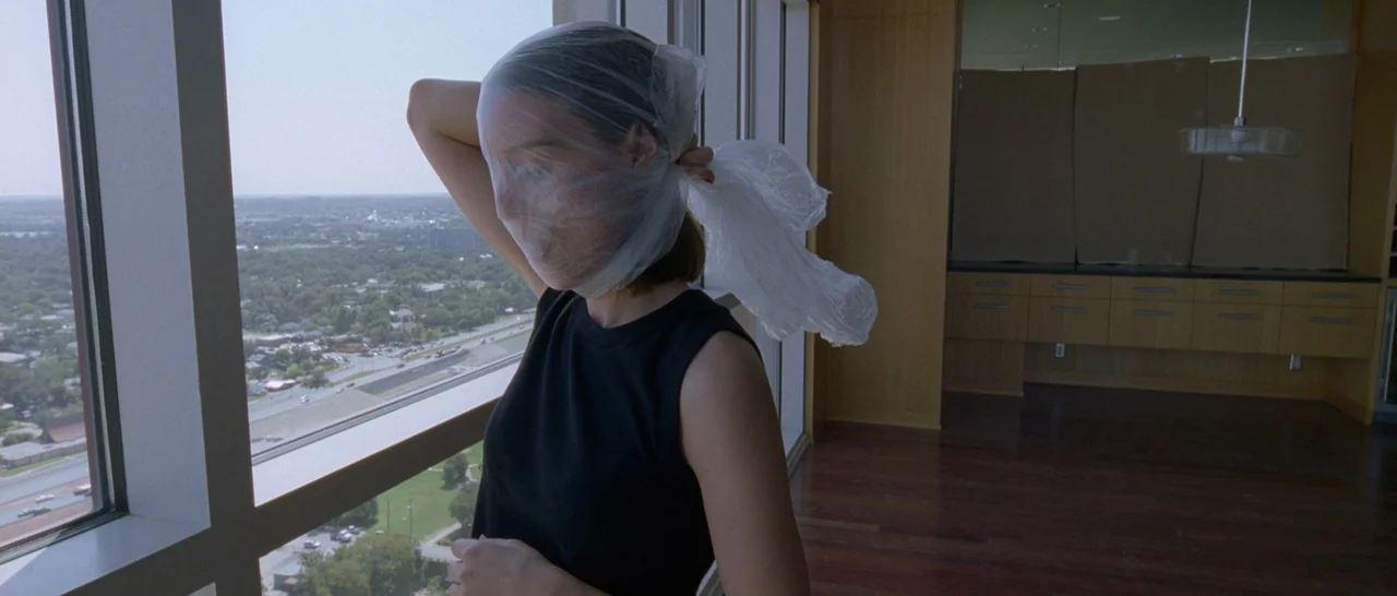Song to Song (2017) movie still: medium — A modern apartment with floor-to-ceiling windows overlooks a city and highway during the day. A woman has…