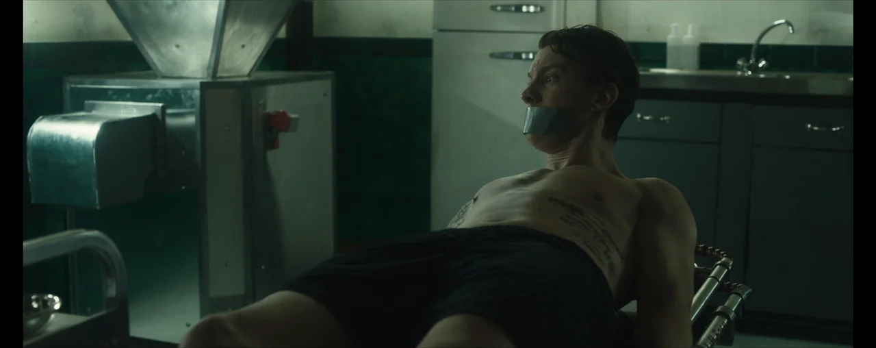 The Wrong Tenant (2022) movie still: medium — A sterile industrial room features metal equipment and dark-painted cabinetry against the walls. A…