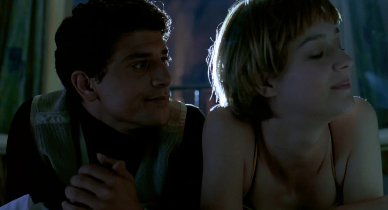The Good Thief (2002) movie still: medium — A dark indoor space features two people lying down near one another at night. A man wearing a mesh vest…