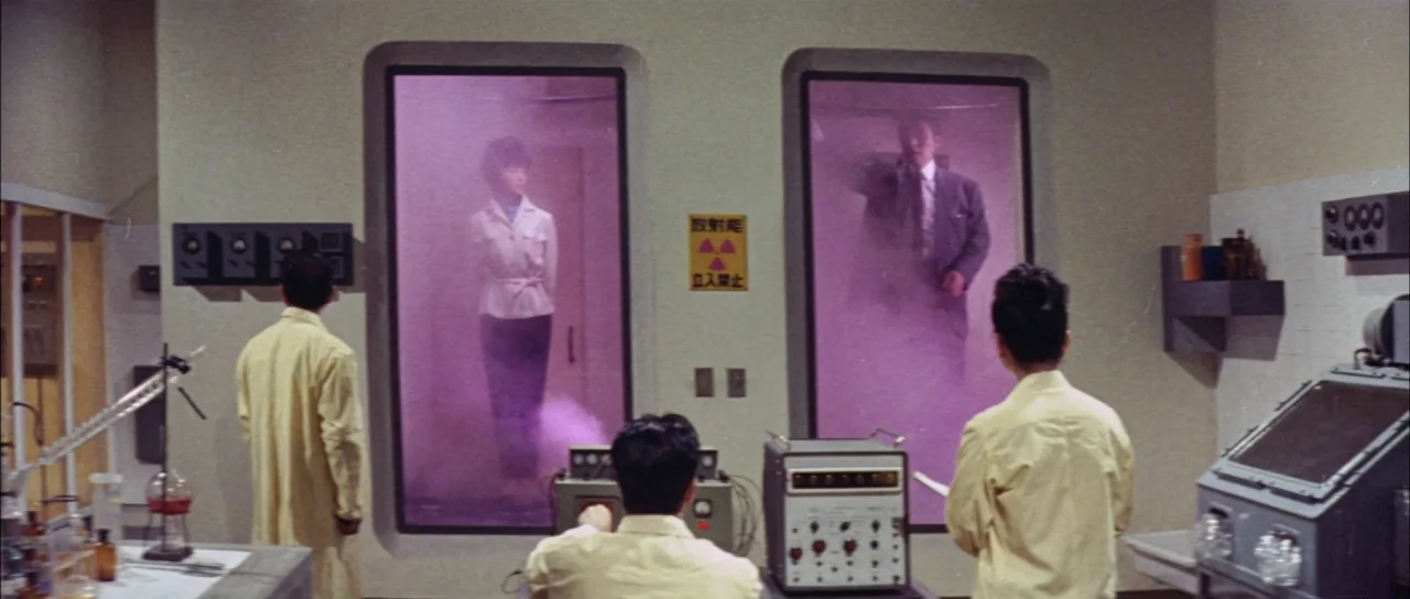 Mothra Vs Godzilla (1964) movie still: wide — A 1960s laboratory features two large glass chambers filled with opaque purple gas. Three scientists…