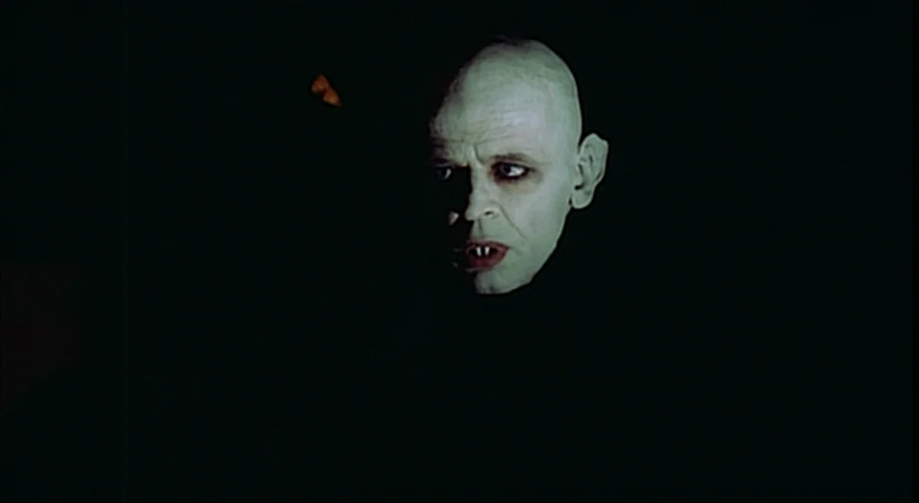 Nosferatu the Vampyre (Nosferatu Phantom Der Nacht) (1979) movie still: closeup — A figure with pale skin and sharp fangs emerges from complete…
