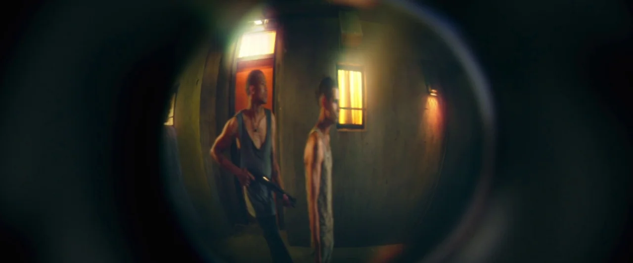 Dredd (2012) movie still: medium — A dark, cramped hallway contains two men appearing through a wide-angle door peephole lens. One man holds a…