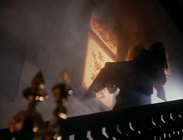 Head of the Family (1996) movie still: medium — A dark staircase hallway filled with thick, visible smoke or haze. A woman stands in silhouette…
