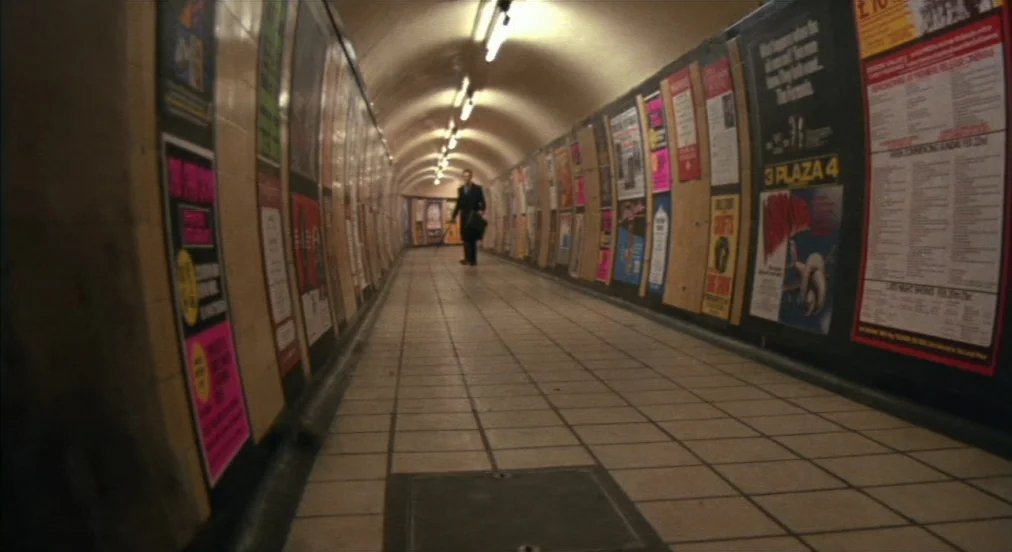 An American Werewolf in London (1981) movie still: wide — A long, curved underground pedestrian walkway features tiled walls covered in colorful…