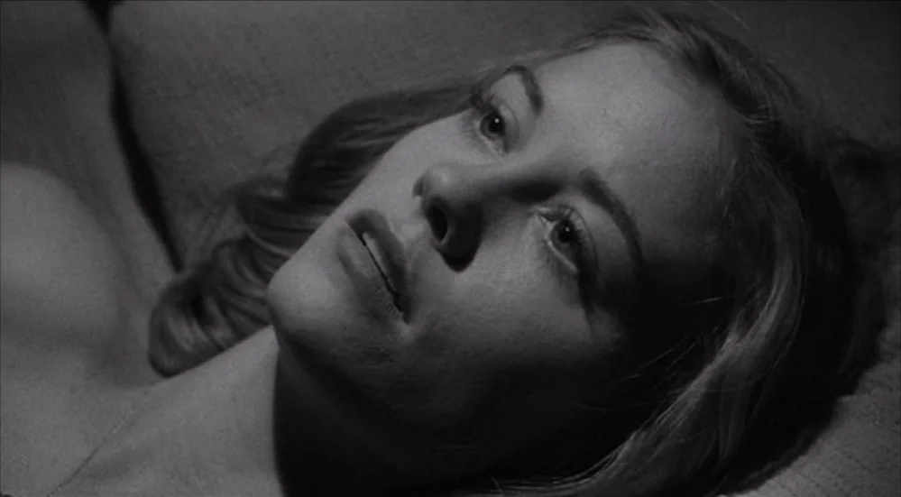 The Last Picture Show (1971) movie still: closeup — A woman lies on a surface in a dark room. She looks upward with her head tilted to the side.