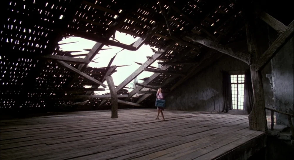 Edward Scissorhands (1990) movie still: wide — A spacious, dilapidated attic features a severely damaged roof with large gaps revealing daylight. A…