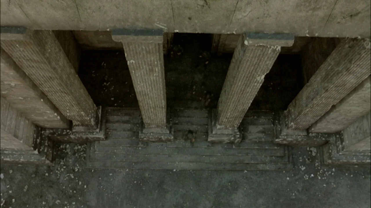 Downfall (2004) movie still: establishing — A top-down view shows the stone entrance of a neoclassical building with fluted columns. Debris and…