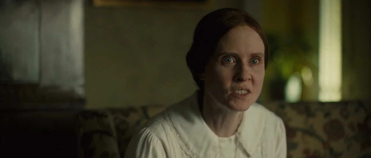 A Quiet Passion (2016) movie still: medium — A dimly lit room with muted-colored walls and patterned fabric upholstery furniture. A woman with…