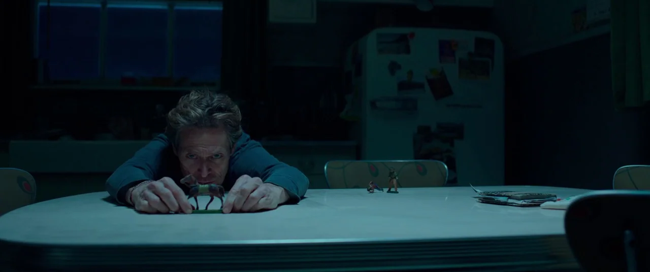 Siberia (2019) movie still: medium — A dimly lit kitchen features a white table where an older man sits slumped. He leans forward with his arms…