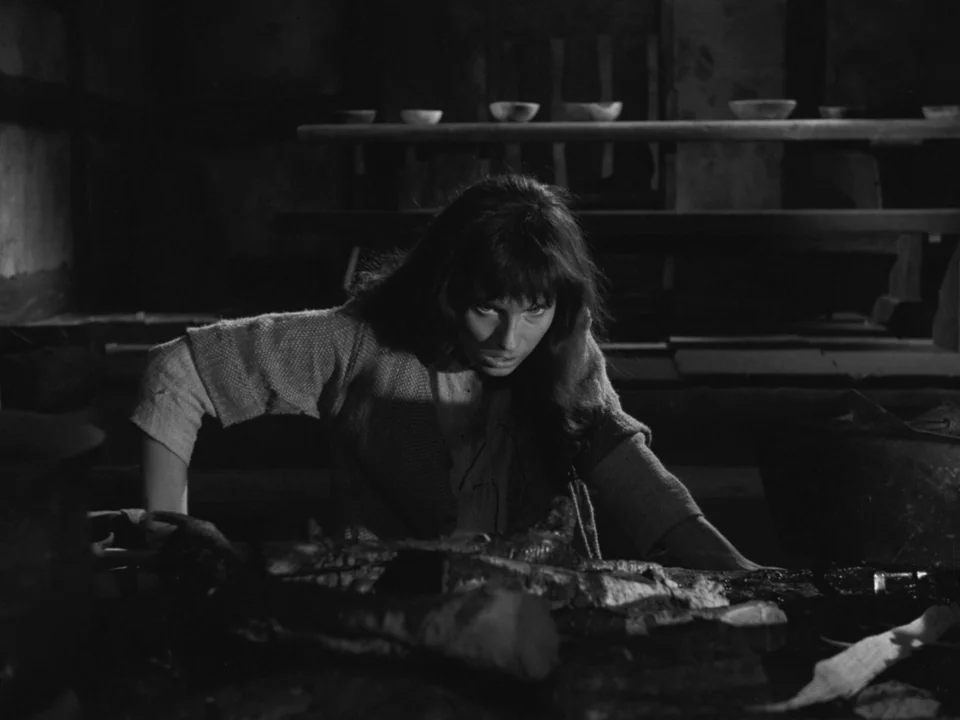 The Virgin Spring (1960) movie still: medium — A dark, rustic interior features a wooden table with simple ceramic bowls lined up. A woman leans…