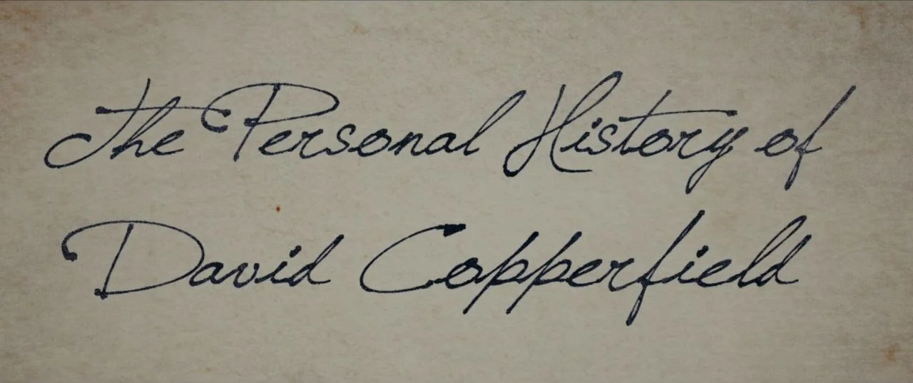 The Personal History of David Copperfield (2019) movie still: closeup — A cream-colored sheet of textured paper displays elegant dark blue cursive…