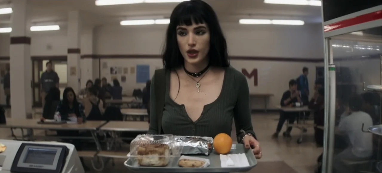 I Still See You (2018) movie still: medium — A high school cafeteria filled with tables and seated students in the background. A young woman walks…