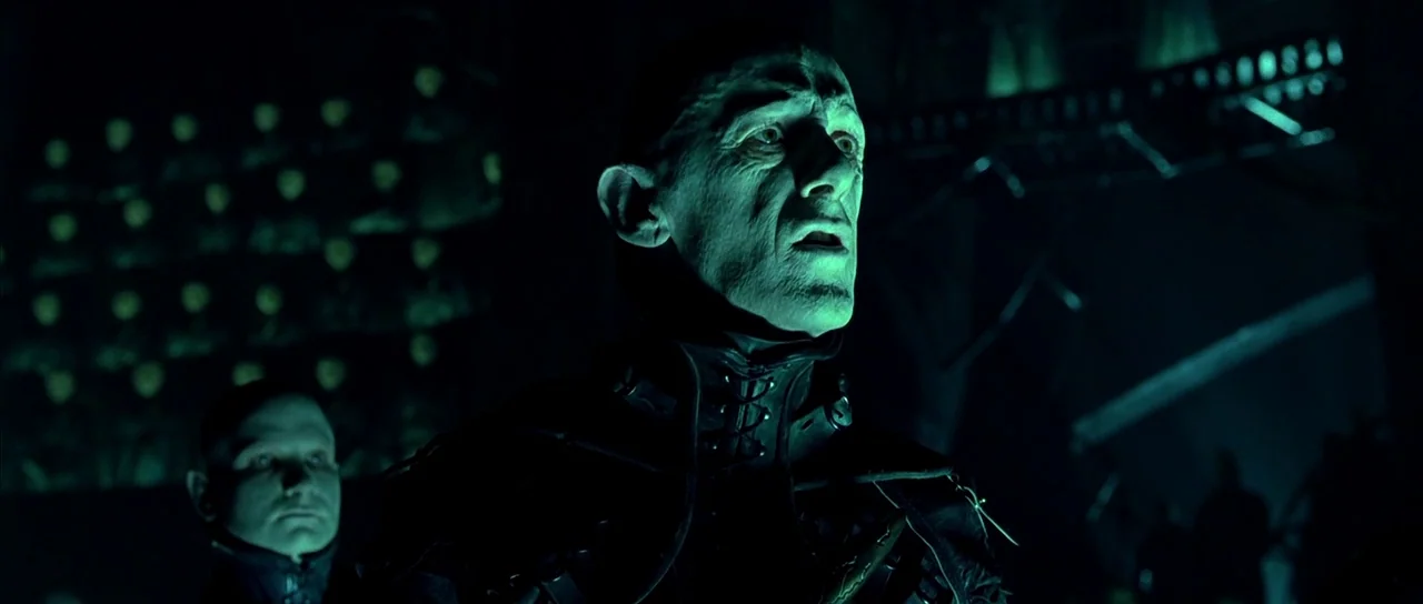 Dark City (1998) movie still: medium — A dark, cavernous stone structure features rows of glowing, skull-like orbs in the distance. An gaunt, bald…