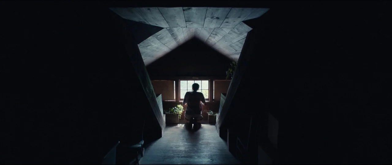 Fall of the House of Usher (1928) movie still: wide — An attic space with dark wooden beams and a triangular ceiling structure. A person kneels on…