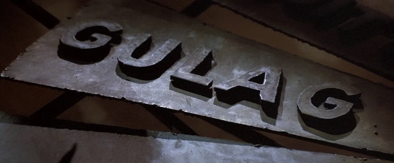 Mad Max Beyond Thunderdome (1985) movie still: closeup — A dark metal plate features raised three-dimensional letters spelling out the word GULAG.…