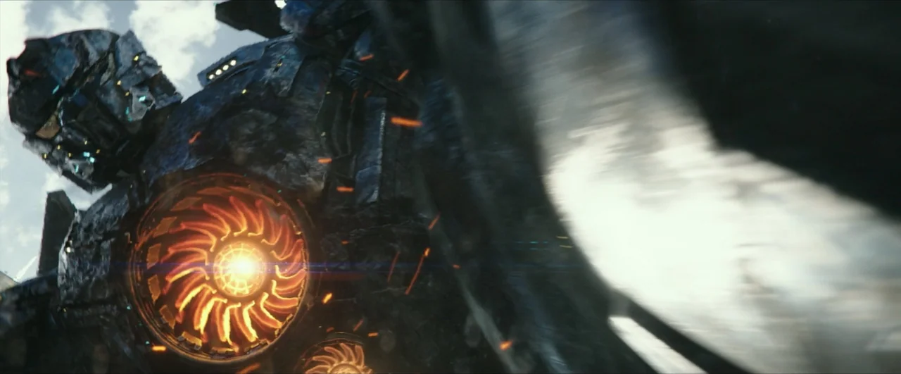 Pacific Rim: Uprising (2018) movie still: closeup — A massive armored mechanical unit with dark textured surfaces ascends through a cloudy sky. The…