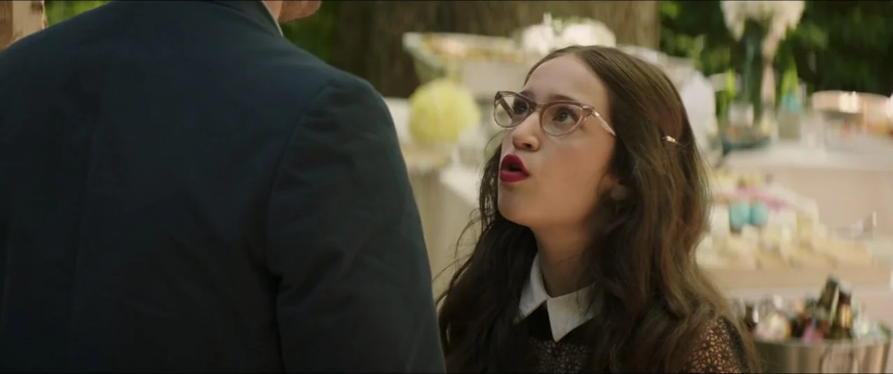 Blockers (2018) movie still: medium — An outdoor social gathering features blurred party tables with food and decor in background. A woman in a…