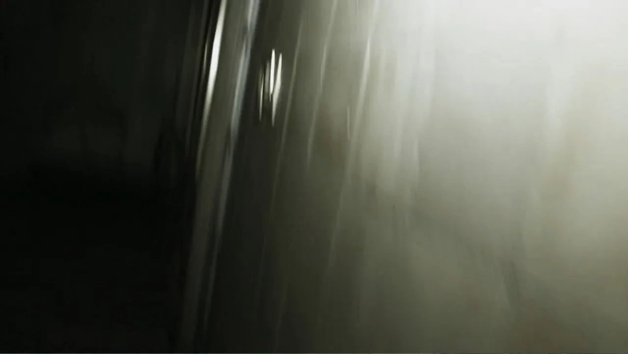 Lost (2010) movie still: establishing — A dark, narrow interior hallway is obscured by thick, bright atmospheric haze or smoke. A single bright…