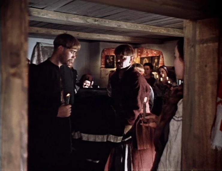 Viy (1967) movie still: medium — A dimly lit, rustic wooden interior features several people gathered for an event. Two men stand in the foreground…